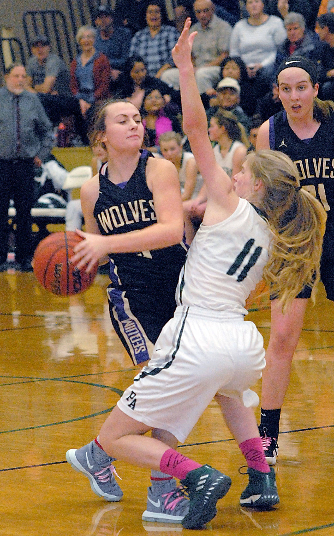 Keith Thorpe/Peninsula Daily News Sequim’s Bobbi Sparks, left, looks for a way around the defense of Port Angeles’ Millie Long during the third quarter on Tuesday night at Port Angeles High School. Looking on at right is Sequim’s Kalli Wiker.