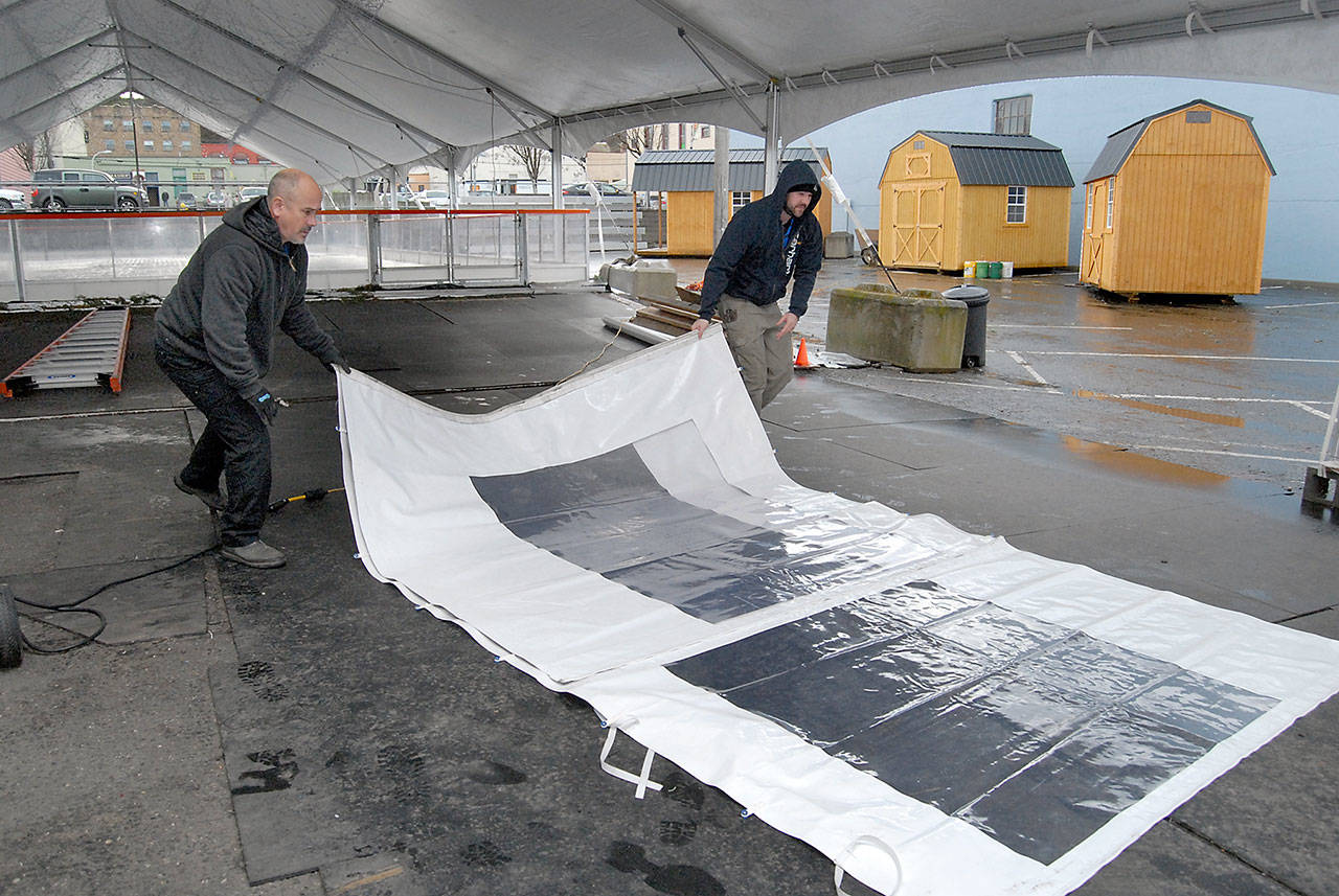 Gary Kettel, left, and his son, Brandon Kettel, facilities workers for 7 Cedars Casino, remove and fold side panels Wednesday from the tent that covered the ice skating rink at the Port Angeles Ice Village in downtown Port Angeles. (Keith Thorpe/Peninsula Daily News)