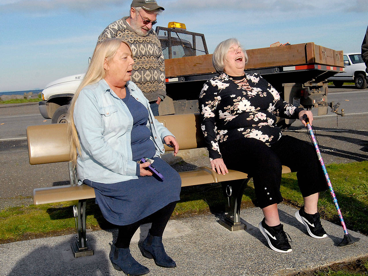 Sisters Karen Borneman of Port Angeles, left, and Sherry Schleufer of Longview, right, were the first to sit on a recycled carbon fiber park bench as brother Dale Gesellchen of Port Angeles looks on after the bench was installed Tuesday near the boat launch on Ediz Hook in Port Angeles. (Keith Thorpe/Peninsula Daily News)