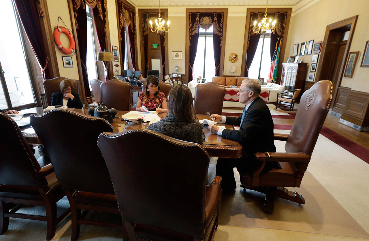 Gov. Jay Inslee, right, meets with staff members in his office as he goes over his State of the State speech Monday. Inslee is scheduled to deliver the annual address today. (Ted S. Warren/The Associated Press)