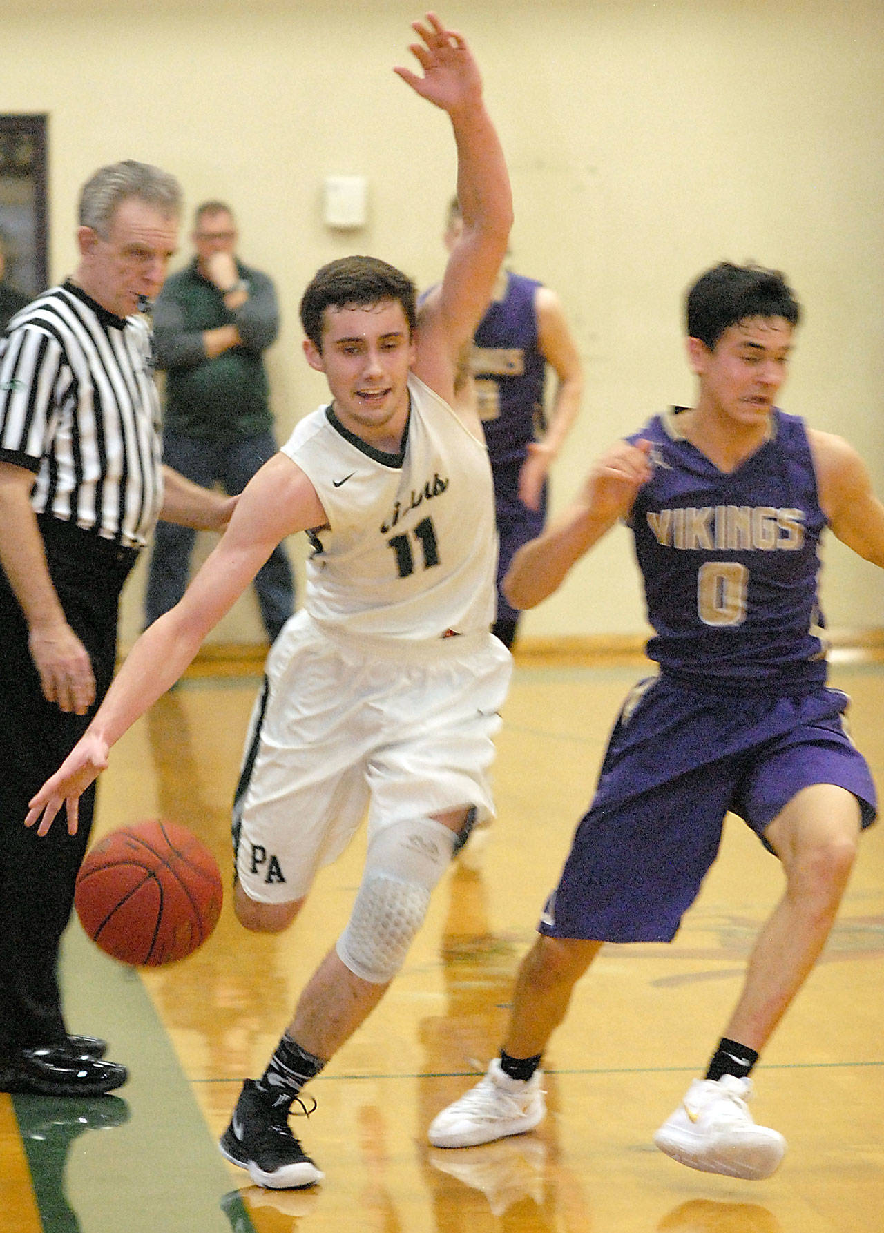 Keith Thorpe/Peninsula Daily News Port Angeles’ Kyle Benedict, center, struggles to keep himself and the ball in bounds while racing North Kitsap’s Johny Olmsted down court as referee John Hayden, left, keeps watch on Friday night at Port Angeles High School.