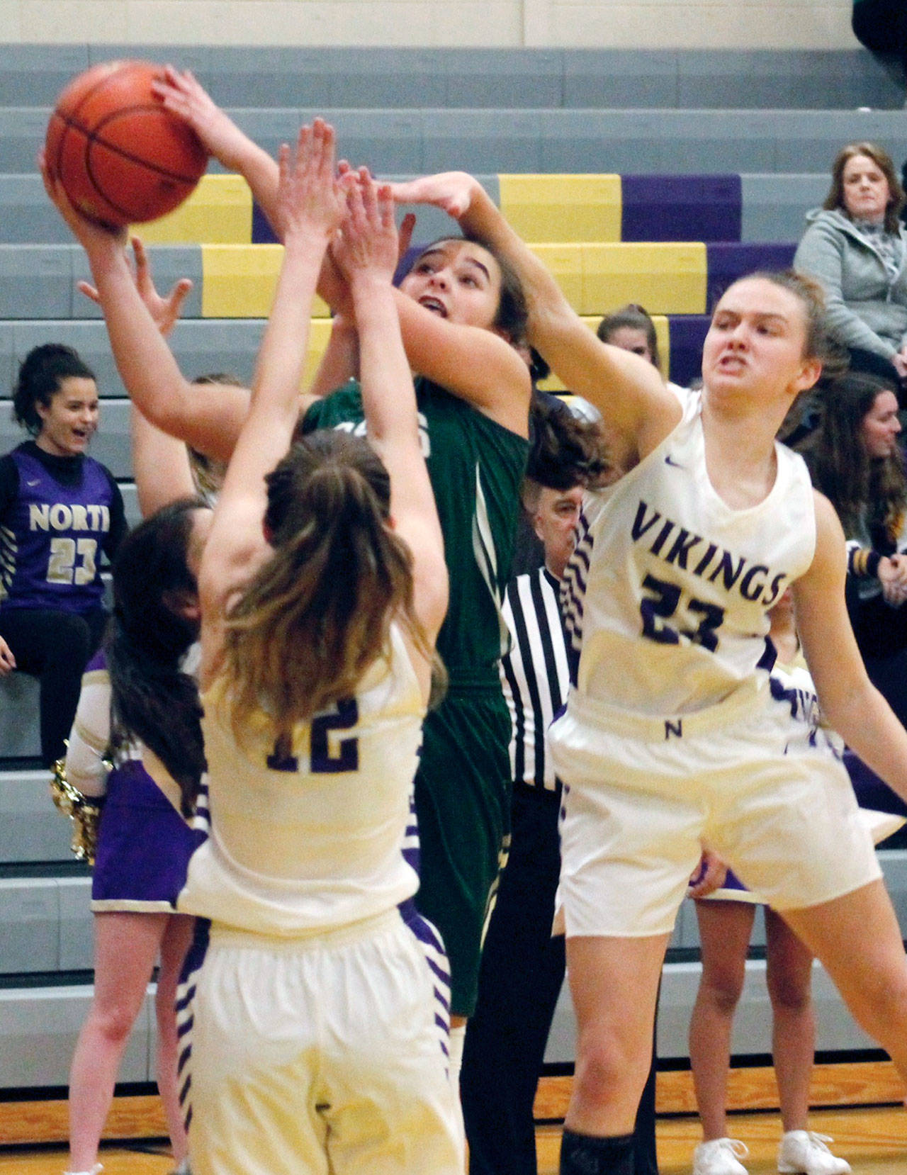 Mark Krulish/Kitsap News Group Port Angeles’ Eve Burke is engulfed by North Kitsap defenders Raelee More, right and Grace Johnson as she goes up for a layup.