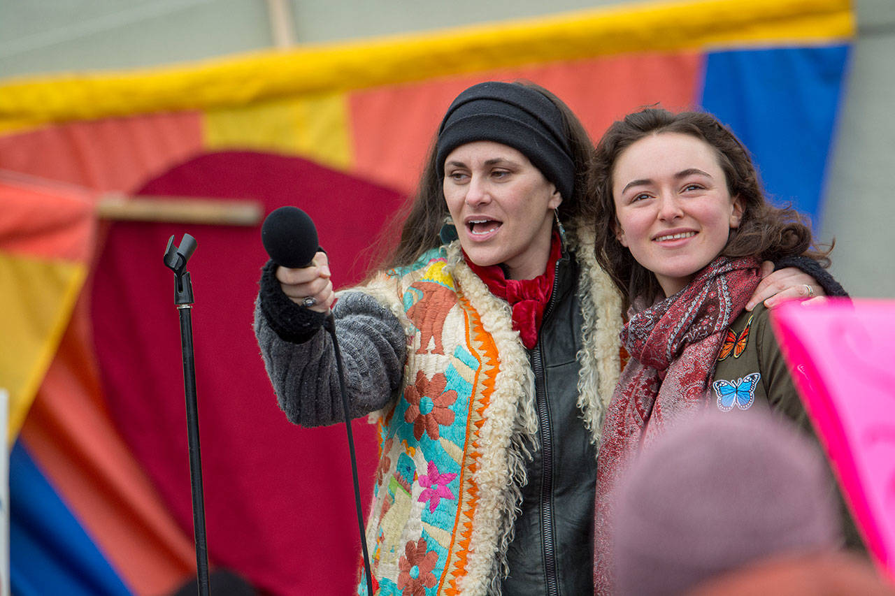 Zhaleh Almaee, left, and Hannah Bahls lead cheers as tribal members offer a blessing at the start of the third annual Olympic Peninsula Womxn’s Wave on Sunday. (Jesse Major/Peninsula Daily News)