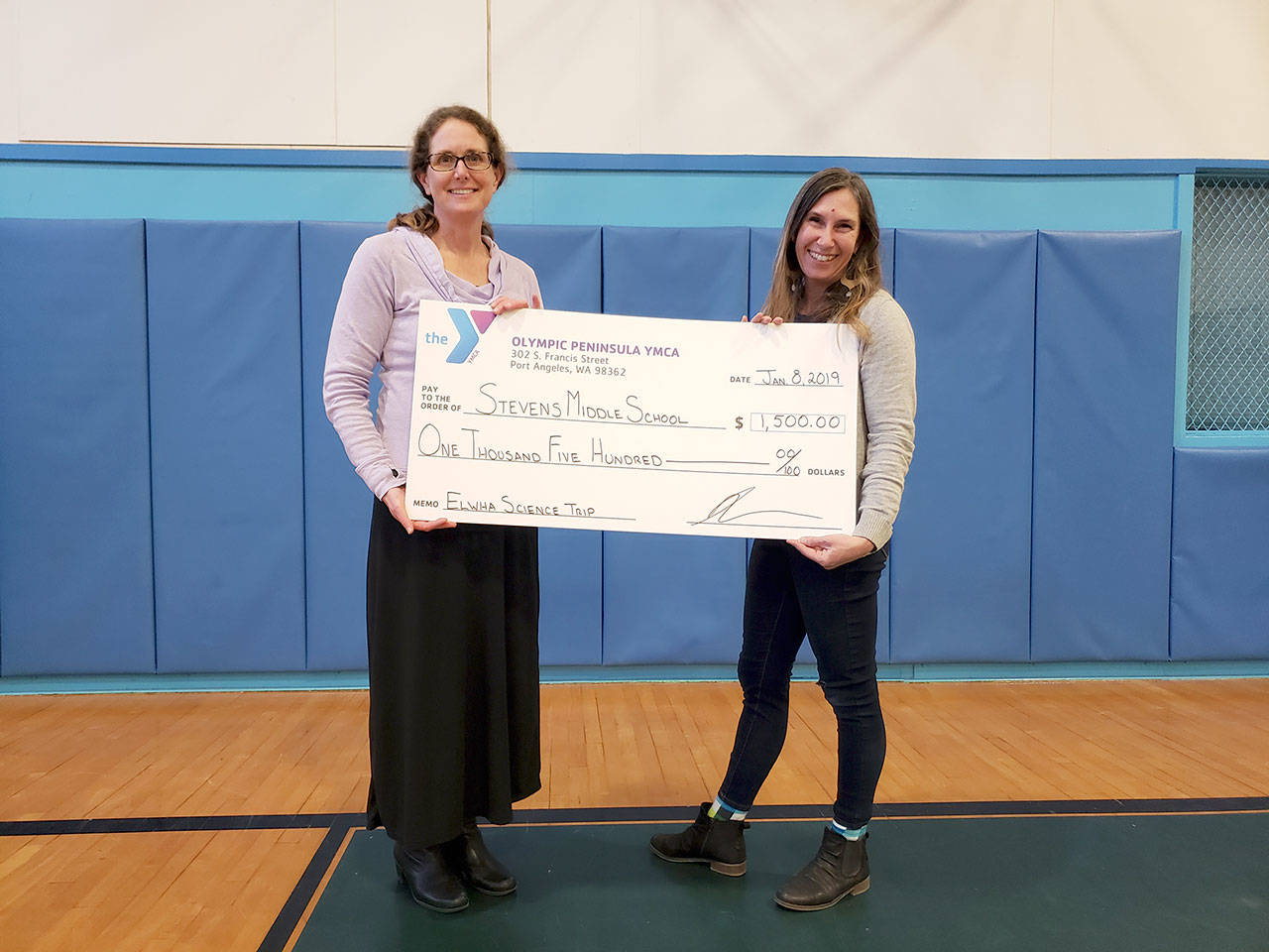 Eighth-grade science teacher Brenda Manson, left, and Christine Loewe, YMCA Dennis Watson Spirit of TEAM Grant Committee chair, hold a check for Stevens Middle School.