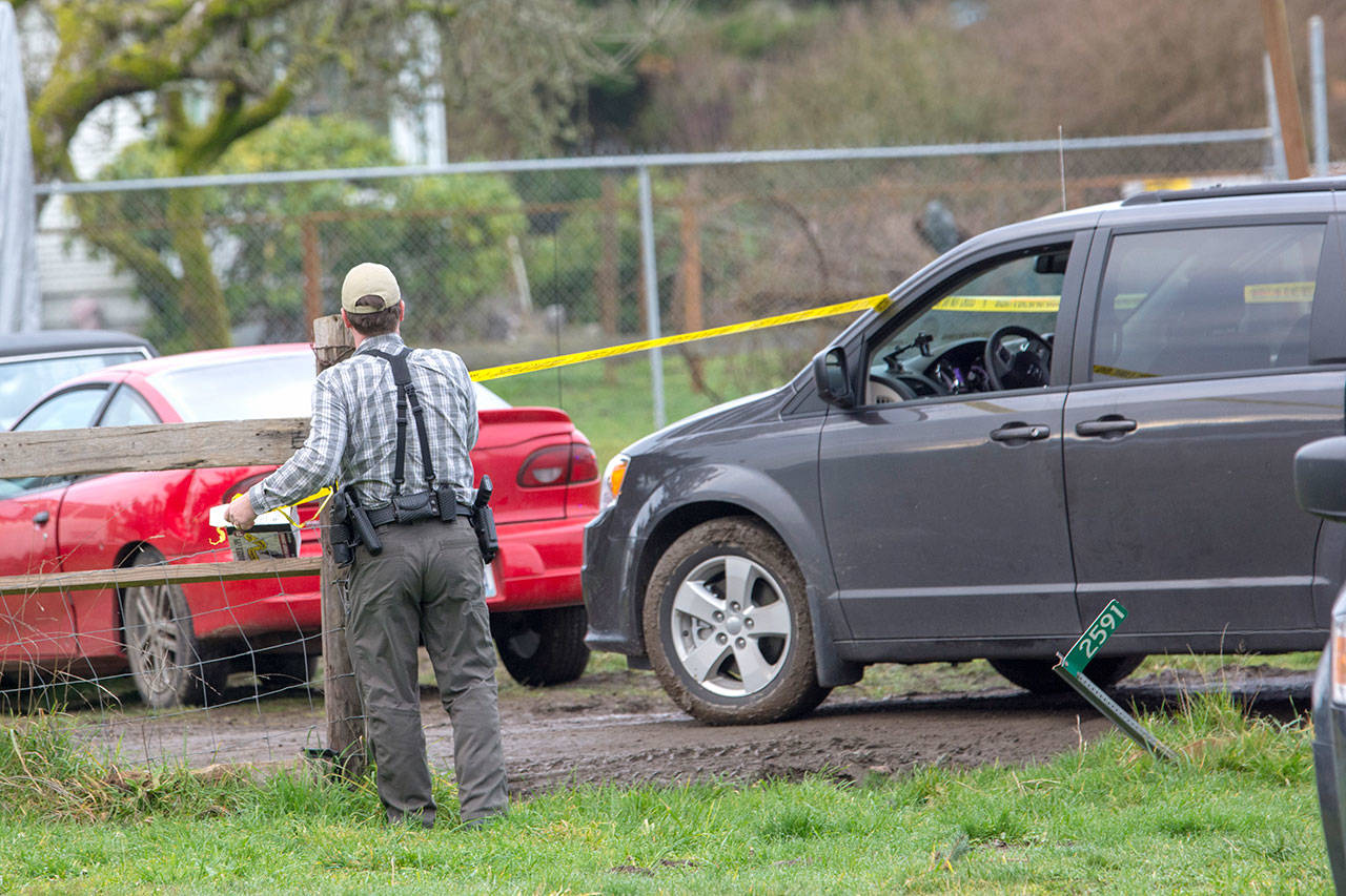 Clallam County Sheriff’s Staff Sgt. John Keegan puts up crime scene tape around a property on Lower Elwha Road where a man was arrested in connection to the triple homicide. (Jesse Major/Peninsula Daily News)