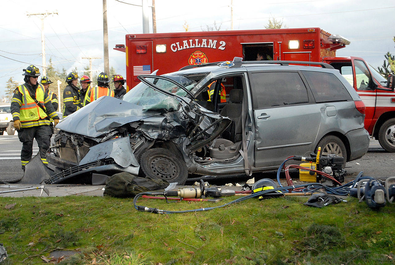 Firefighters from Clallam County Fire District No. 2 work at the scene of a collision between a mini van and a semi-trailer truck on U.S. Highway 101 and Monroe Road east of Port Angeles on Friday. Two people were injured in the wreck which tied up traffic in both directions. (Keith Thorpe/Peninsula Daily News)
