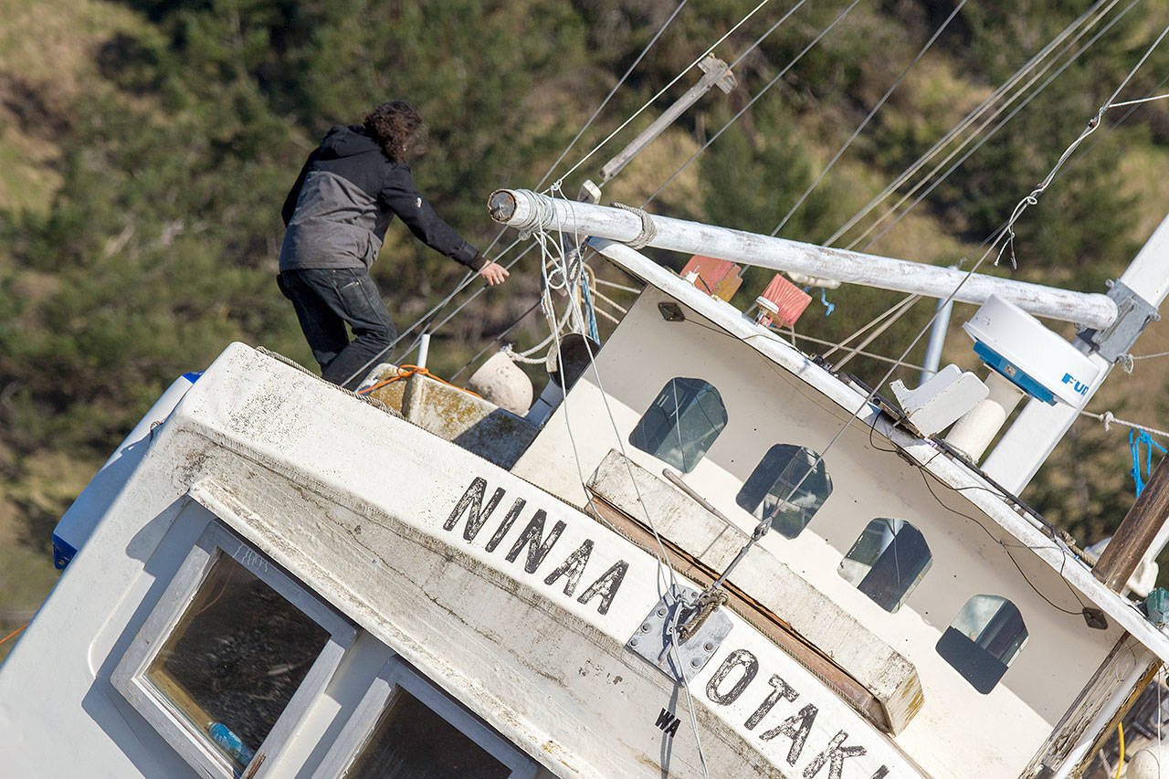 Tyler Vega, captain of the Ninaa Ootaki, climbs aboard the beached vessel Tuesday. She ran ashore at Beckett Point during a storm in December. (Jesse Major/Peninsula Daily News)