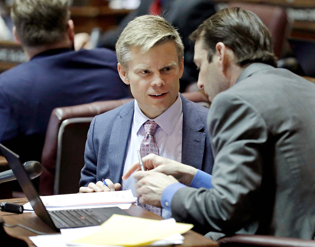Sen. Jamie Pedersen, left, D-Seattle, talks with a colleague on the Senate floor in Olympia. Pedersen introduced a bill Thursdaythat he says moves the Legislature toward more transparency — but within limits. (The Associated Press)