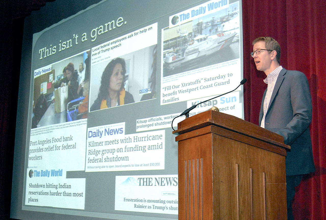 U.S. Rep. Derek Kilmer speaks about the recent government shutdown against a backdrop of newspaper headlines during a town hall meeting at Peninsula College in Port Angeles. (Keith Thorpe/Peninsula Daily News)