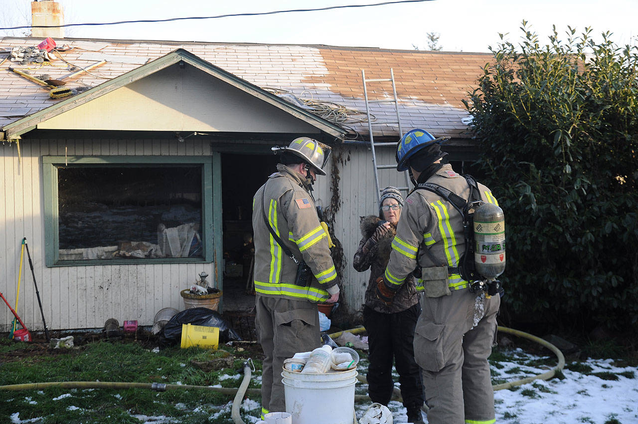 Clallam County Fire District No. 3 personnel talk with Pearl Williams, one of two residents living in a home near Carlsborg that was damaged by an early morning fire Thursday. Williams was not home at the time of the fire, and no people were hurt in the incident, district officials said. (Michael Dashiell/Olympic Peninsula News Group)