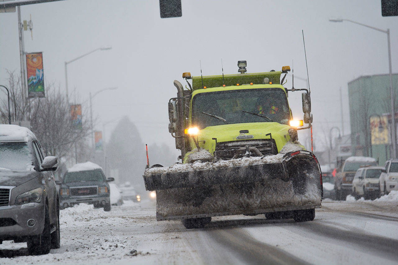 A state Department of Transportation plow makes its way through downtown Port Angeles as snow begins to fall Monday afternoon. (Jesse Major/Peninsula Daily News)