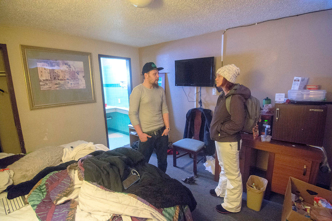 Ryan Petka, who had been sleeping outside before the snowstorms hit, talks with Amy Miller who coordinates Volunteers in Medicine of the Olympics’ Rediscovery program on Tuesday. Miller spent Tuesday morning checking on people who had been provided hotel rooms during the recent winter weather. (Jesse Major/Peninsula Daily News)