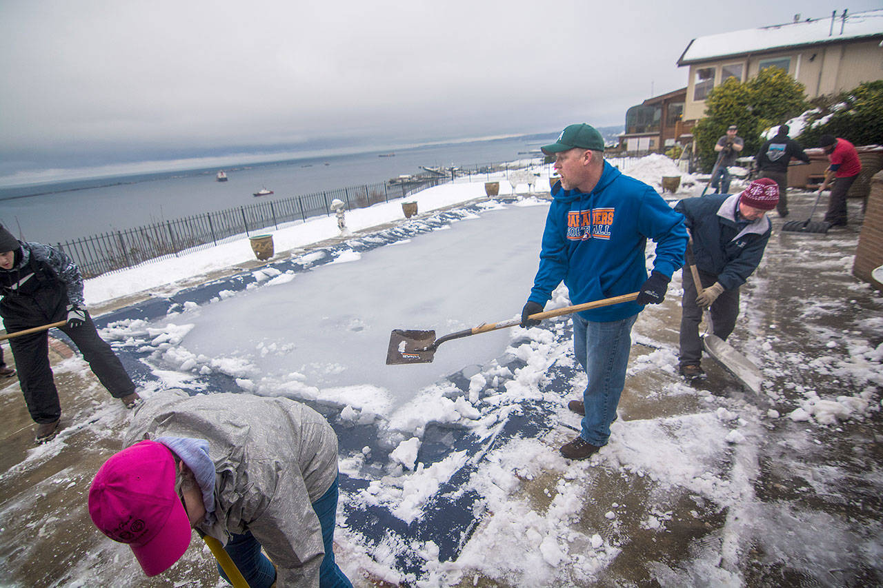 About 20 people came together to clear snow from the home of a longtime Port Angeles basketball coach while he recovers from surgery in Seattle on Tuesday. (Jesse Major/Peninsula Daily News)