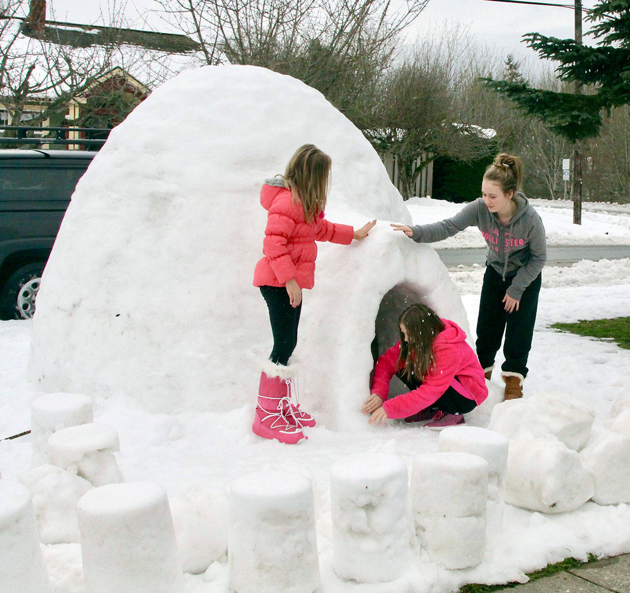Anella Henning, age 7, Kendra Dickinson, age 11, and Mallory Dickinson, age 13, inspect the craftsmanship of the igloo constructed by families at Fifth and Albert streets in east Port Angeles this week. (Dave Logan/for Peninsula Daily News)