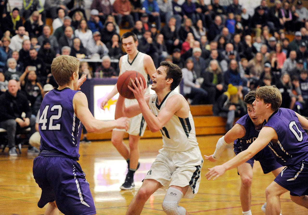 Michael Dashiell/Olympic Peninsula News Group Port Angeles’ Kyle Benedict (with ball) looks to shoot while defended by, from left, Sequim’s Erik Christiansen, Nate Despain and Kyler Rollness during the Riders’ 50-40 district win over the Wolves at Sequim High School.