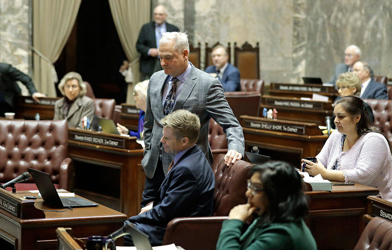 Sen. Reuven Carlyle, D-Seattle, standing center, watches with Sen. Jaime Pedersen, D-Seattle, seated center, as votes are tallied Friday on the Senate floor following debate in Olympia on a measure that would repeal the death penalty in Washington state. (Ted S. Warren/The Associated Press)