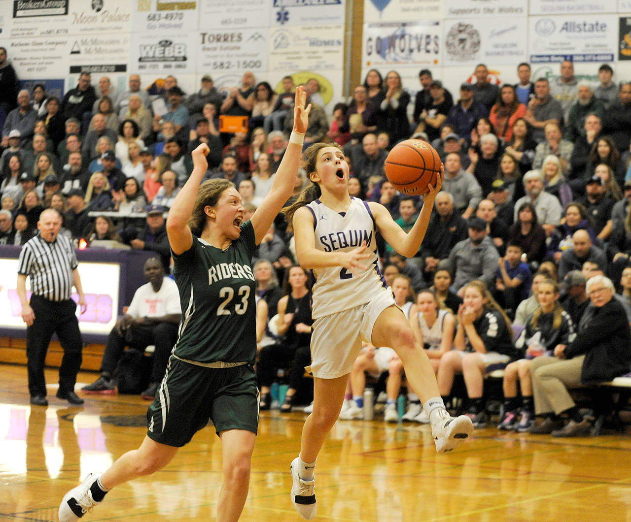 Michael Dashiell/Olympic Peninsula News Group Port Angeles’ Madison Cooke, left, attempts to block the layup attempt of Sequim’s Jessica Dietzman during a game last month. The two teams learned their state regional opponents, dates and game times Tuesday.