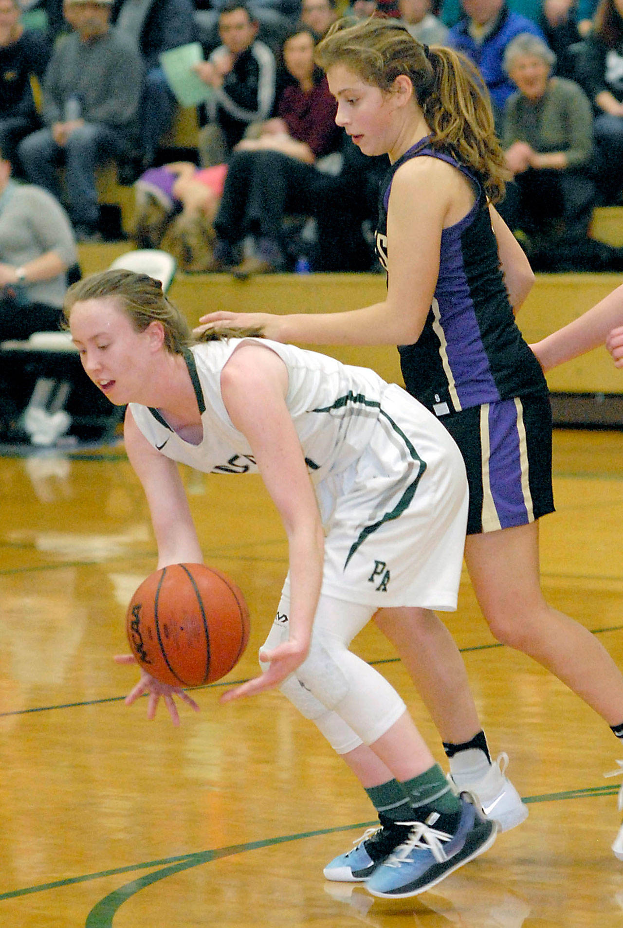 Keith Thorpe/Peninsula Daily News Port Angeles’ Mikkiah Brady, left, scoops up a loose ball as Sequim’s Jessica Dietzman looks on during their game in January,