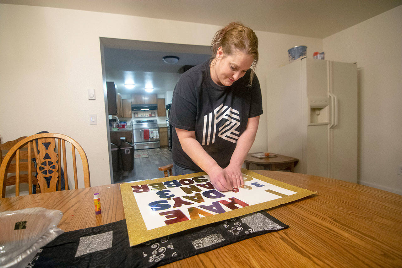 Jenni Tiderman puts together her sign declaring that she has 364 days sober Thursday. She celebrated one year clean from drugs and alcohol Saturday. (Jesse Major/Peninsula Daily News)