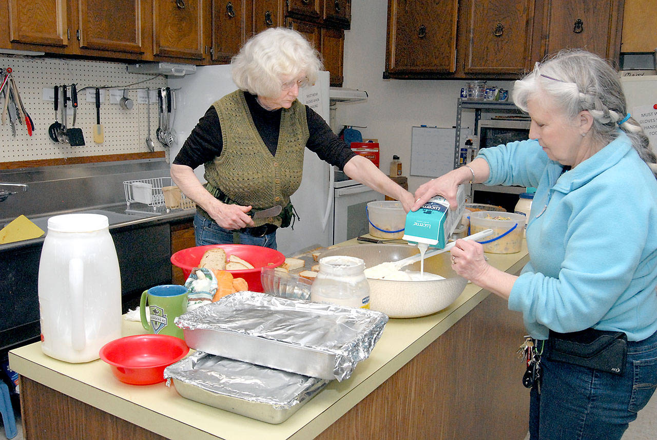 Ingrid Carmen, social justice advocate for The Answer For Youth (TAFY) homeless assistance organization, left, and TAFY director Susan Hillgren prepare a meal for the organization’s clients on Wednesday in Port Angeles. (Keith Thorpe/Peninsula Daily News)