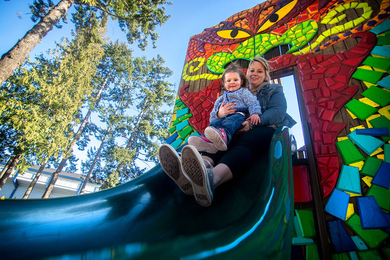 Mary Helgeson and her 2-year-old daughter Kamrynn go down a slide at the Dream Playground in Port Angeles. (Jesse Major/Peninsula Daily News)