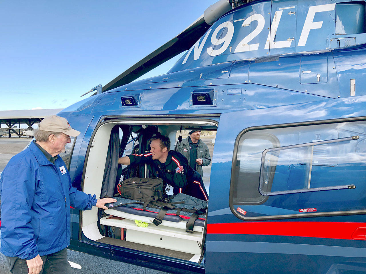 Alan Barnard, Port Angeles Disaster Air Response Team coordinator, looks on as Life Flight crew member/paramedic Nick Lane prepares the company’s helicopter to assist with emergency response efforts at the scene of the logging helicopter crash.