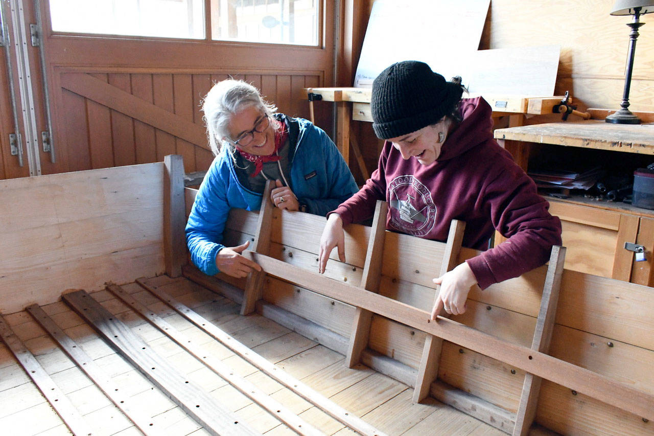 Northwest Maritime Center’s Associate Program Coordinator Chrissy McLean and shipwright woodworker apprentice Kat Murphy check the seat riders for adjustment on Otter Pride, a 12-foot work punt boat being built by students in the Girls’ Boat Project. (Jeannie McMacken/Peninsula Daily News)