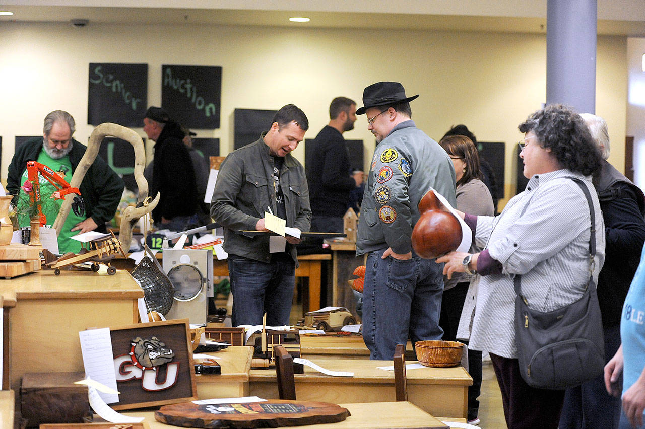 A group of bidders looks over a few of the many items up for bid at last year’s auction. (Lonnie Archibald/for Peninsula Daily News)