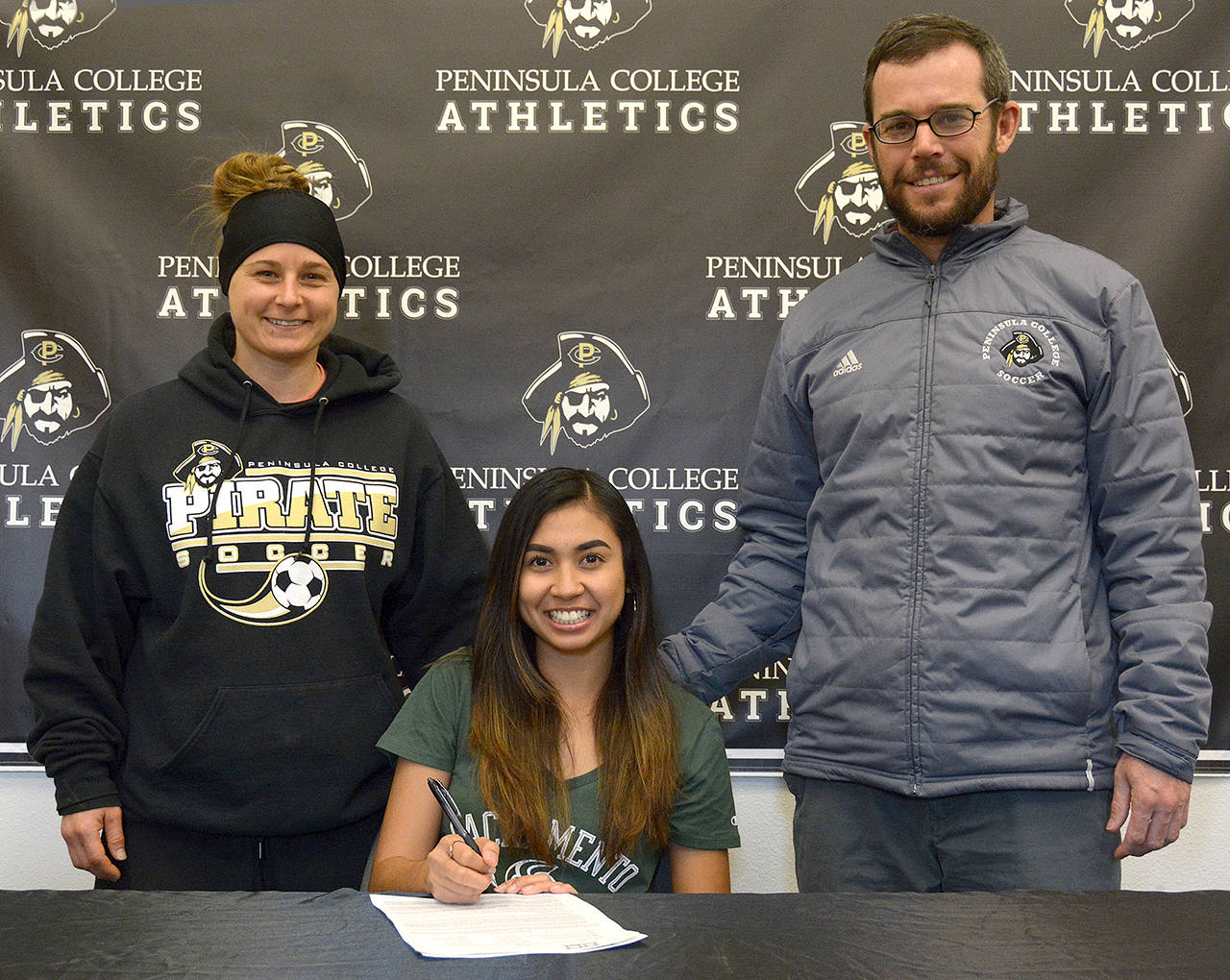 Rick Ross/Peninsula College Athletics Peninsula College’s Shantel Torres-Benito, center, signs a letter of intent to play soccer for NCAA Division I Sacramento State while joined by Pirate assistant coach Jordyn Shaffer and head coach Kanyon Anderson.