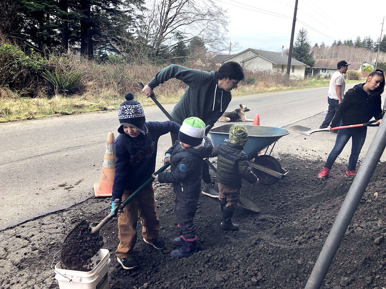 Natalie Maxson helps shovel gravel with two boys at the entrance to a new tsunami evacuation trail off Backtrack Road in Neah Bay.