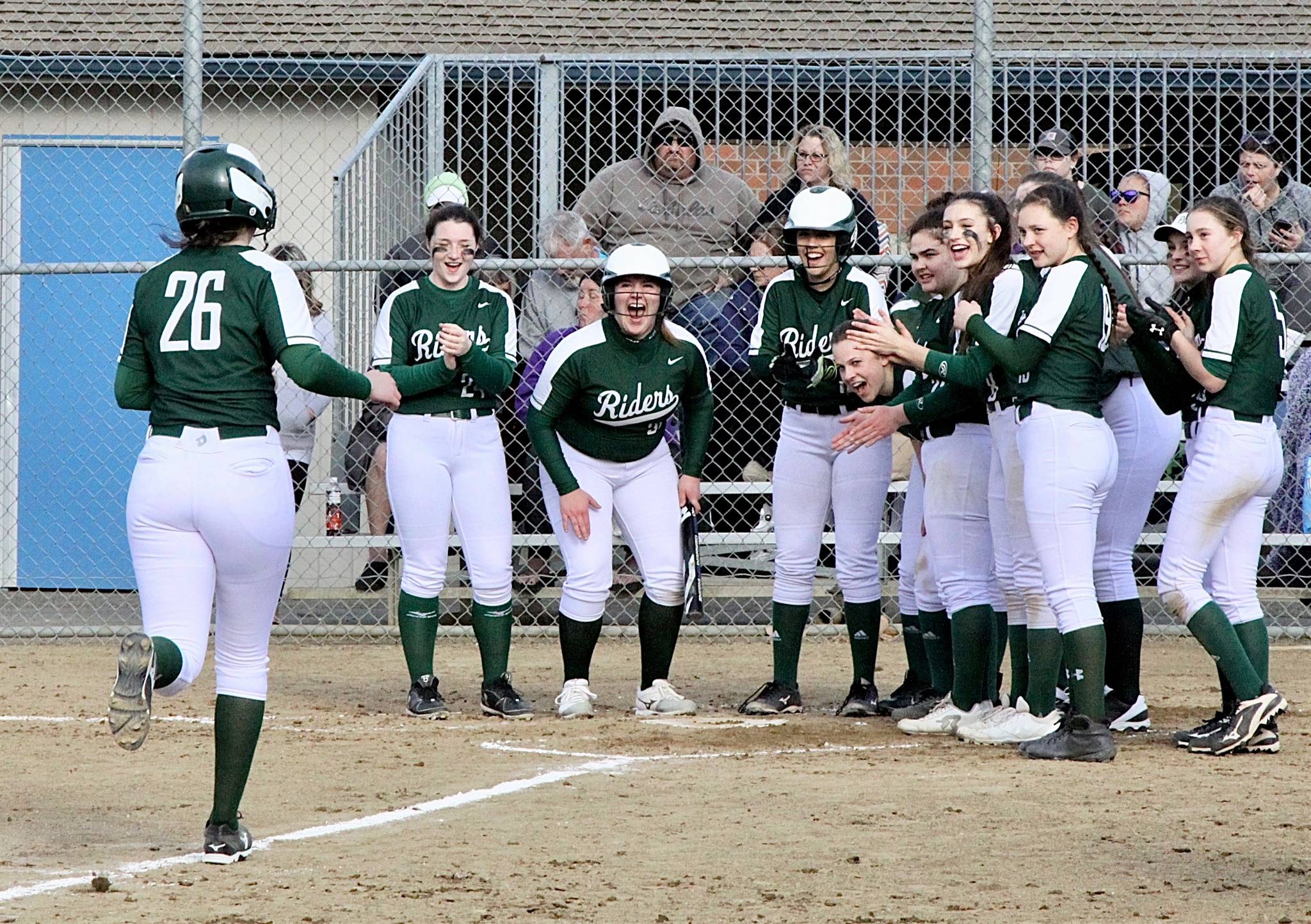 Port Angeles’ Aeverie Politika (26) is greeted by her Roughrider teammates after hitting an out-of-the-park home run against Sequim on Thursday. Port Angeles won 10-1. (Dave Logan/for Peninsula Daily News)