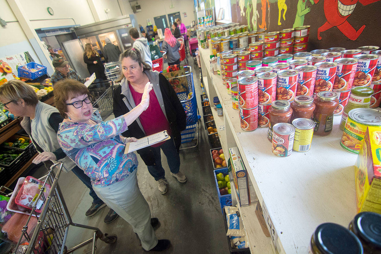 Port Angeles Food Bank volunteer and board member Kathi Sparkes, left, helps Sandra Gowdy through the food bank Monday. The food bank recently adopted a “grocery store” model that allows clients to choose the items they need. (Jesse Major/Peninsula Daily News)