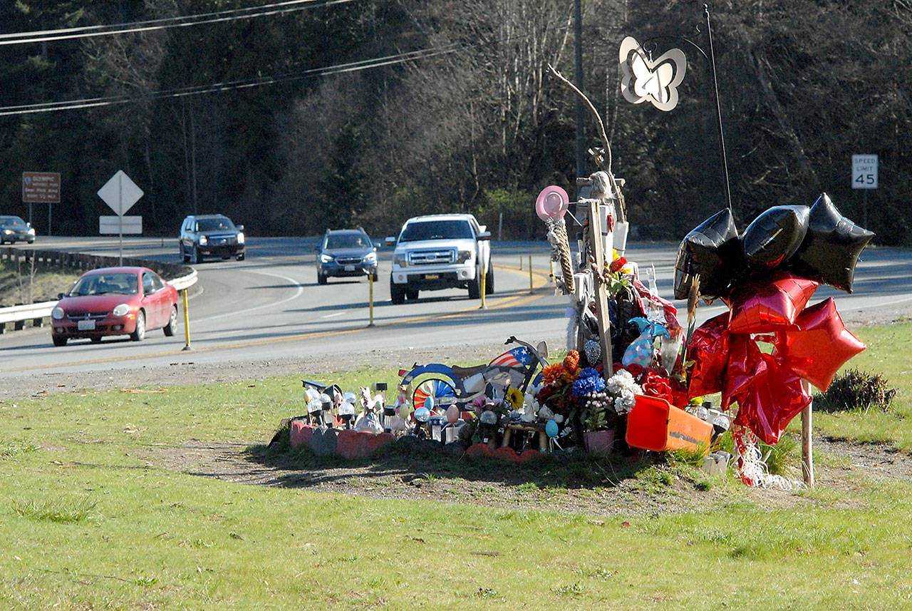 Traffic passes a roadside memorial on Tuesday to Brooke Bedinger, who died in a motorcycle wreck on U.S. Highway 101 at Morse Creek near Port Angeles on June 21. The state House has proposed funding for a barrier. (Keith Thorpe/Peninsula Daily News)