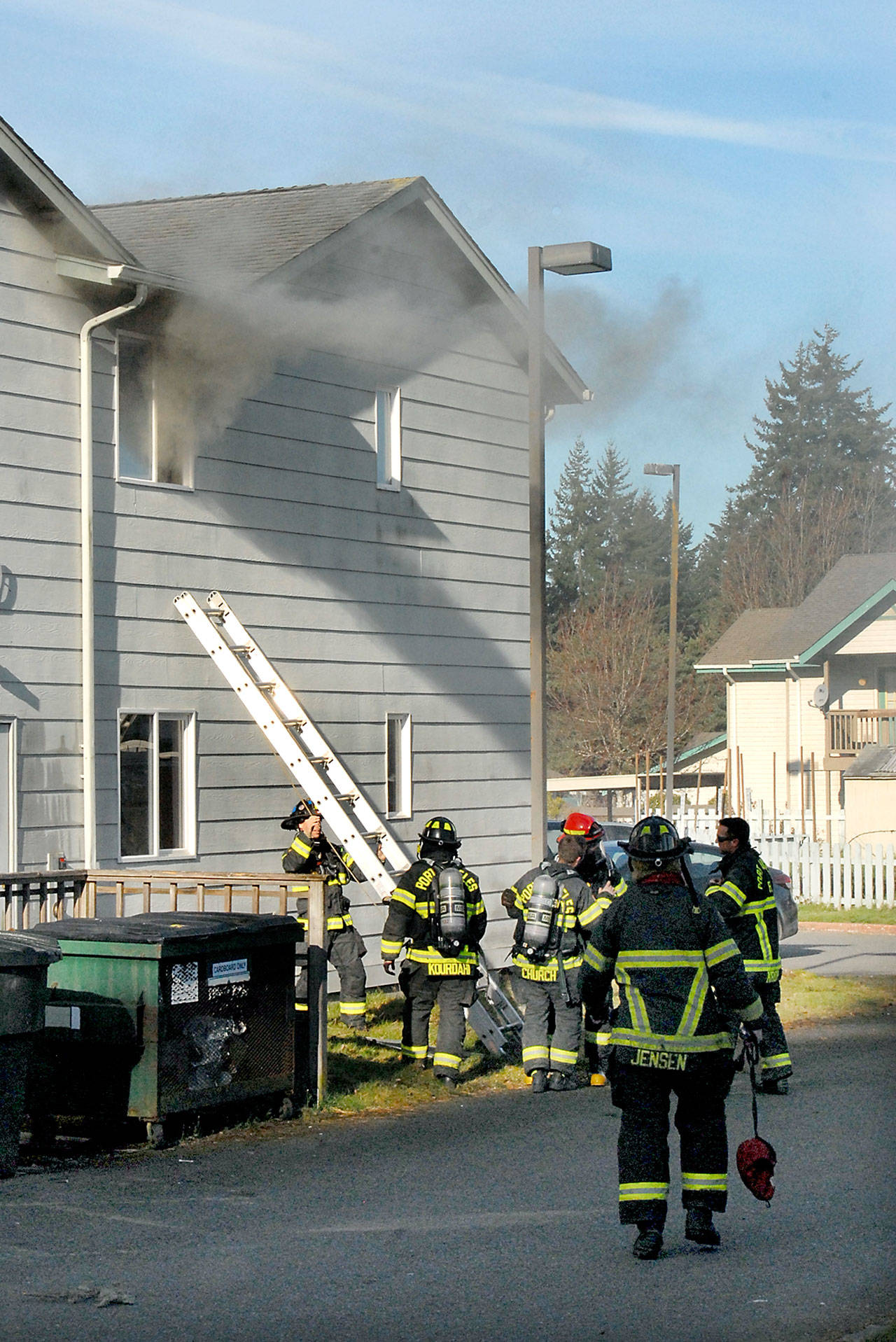 Smoke pours from the second floor window of unit D-15 at Evergreen Family Village in Port Angeles as firefighters extinguish a blaze in the building on Friday morning. (Keith Thorpe/Peninsula Daily News)