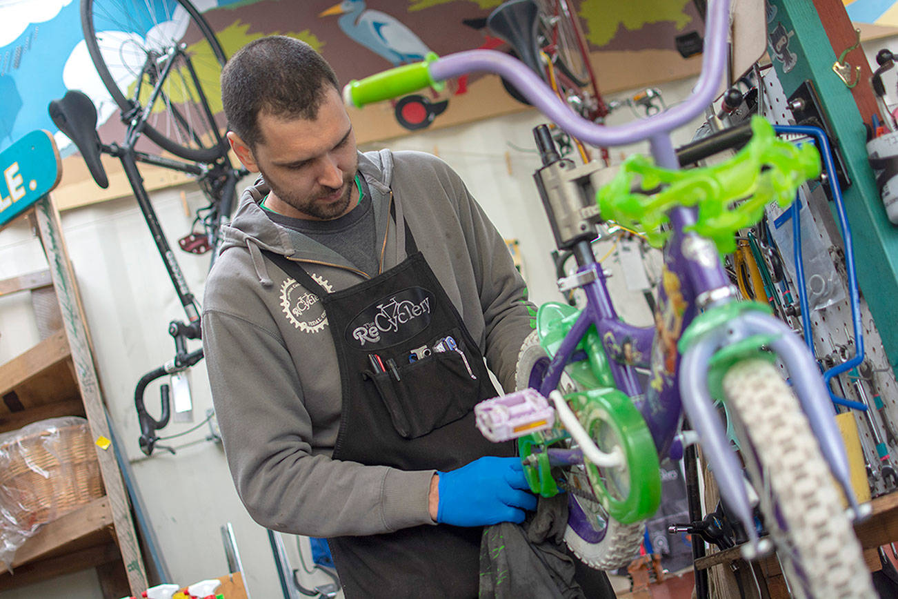 Mechanic CJ Knoph works on a bike at the ReCyclery on Wednesday. (Jesse Major/Peninsula Daily News)