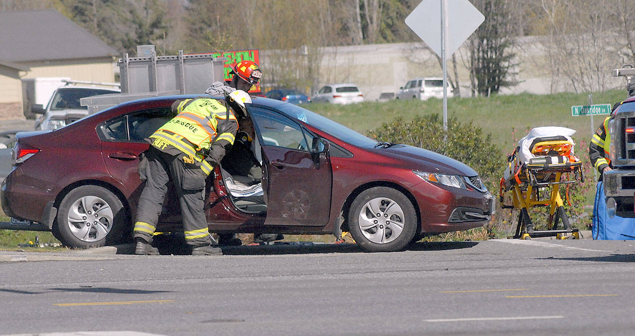 Clallam County Fire District 2 Assistant Chief Dan Huff, front, looks in at the victim of a collision involving three vehicles at the intersection of U.S. Highway 101 and Kolonels Way near the Port Angeles Walmart Supercenter on Tuesday. (Keith Thorpe/Peninsula Daily News)