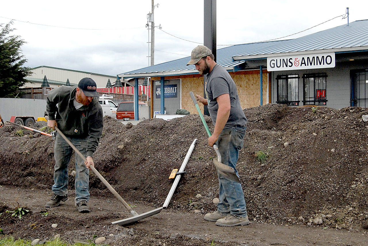 Ryan Dickinson, left, and Anthony LaJambe of Sequim-based We Dig It excavating company prepare ground in front of FREDS Guns near Carlsborg on Tuesday in preparation for the installation of barricades in front of the building. (Keith Thorpe/Peninsula Daily News)