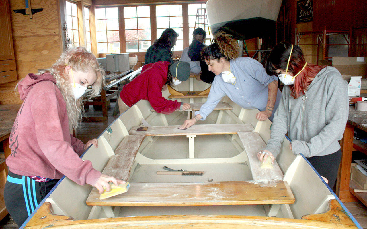 Students and instructors in the Real World Readiness program at the Northwest Maritime Center in Port Townsend sand with the grain on a wooden boat Wednesday. (Brian McLean/Peninsula Daily News)