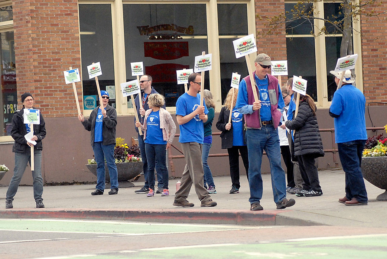 Members of the faculty and staff of Peninsula College hold signs on Tuesday at the Conrad Dyar Memorial Fountain in downtown Port Angeles to raise awareness of state underfunding of the state’s community and technical colleges. The informational picket was set up to urge state legislators to increase the budget for the college system and its employees. (Keith Thorpe/Peninsula Daily News)