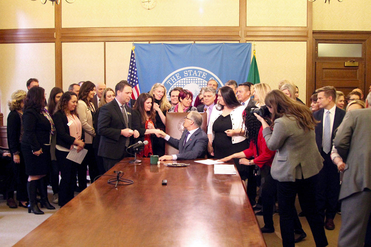 Gov. Jay Inslee shakes hands with Dinah Griffey after signing Senate Bill 5649. Inslee mentioned both Rep. Dan Griffey and his wife Dinah Griffey in his remarks on the bill. (Emma Epperly, WNPA Olympia News Bureau)