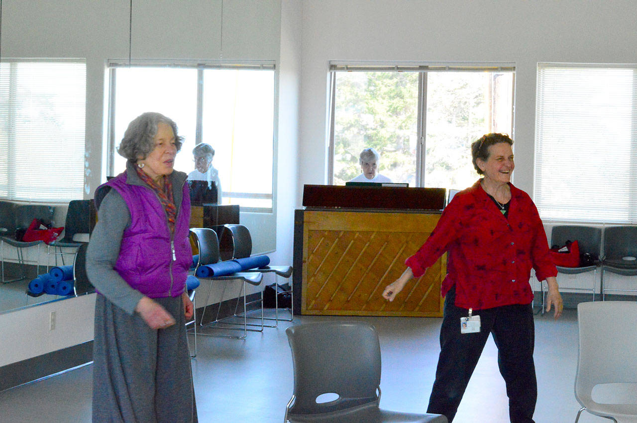 Myrna Eden, left, and Tracy Ware partake in a Dance for Parkinson’s class in Port Townsend. Hazel Johnson plays piano behind them. (Diane Urbani de la Paz/for Peninsula Daily News)