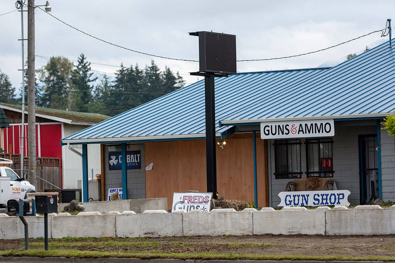 FREDS Guns in Sequim is boarded up and surrounded by concrete blocks Monday, a week after someone drove heavy equipment through the front and stole 20 to 30 handguns. (Jesse Major/Peninsula Daily News)