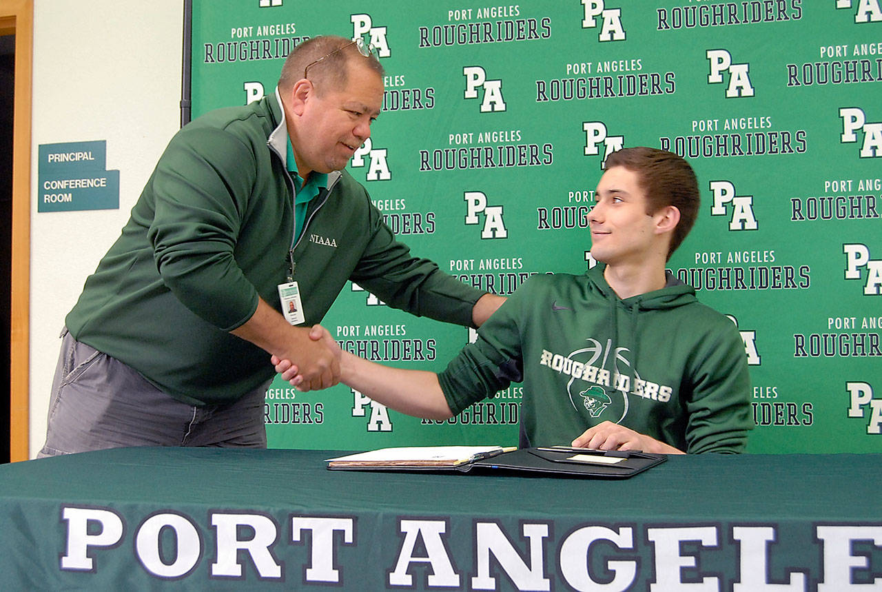 Keith Thorpe/Peninsula Daily News Port Angeles High School athletic director Dwayne Johnson, left, offers his congratulations to senior Kyle Benedict after Benedict signed a letter of intent to attend Lower Columbia College in Longview during a signing ceremony on Wednesday at the high school.