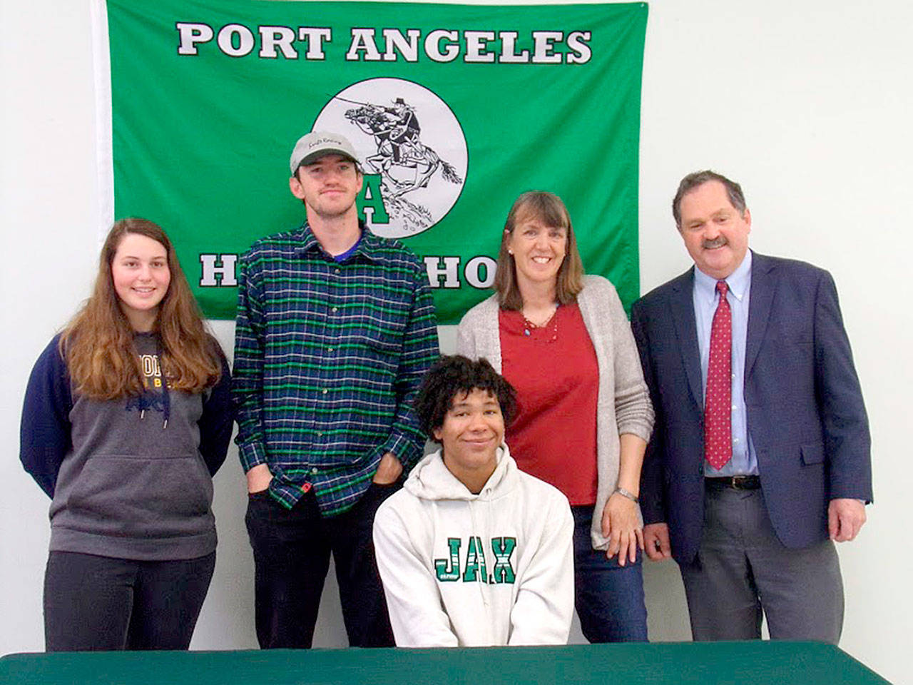 Olympic Peninsula Rowing Association rower Nathan Mishler, seated, signed this week to row for Jacksonville University in Florida. Joining him at his signing ceremony on Monday were, from left, OPRA coaches Maria England, Calum Swinford, Debby Swinford and OPRA board president Scott Kennedy.