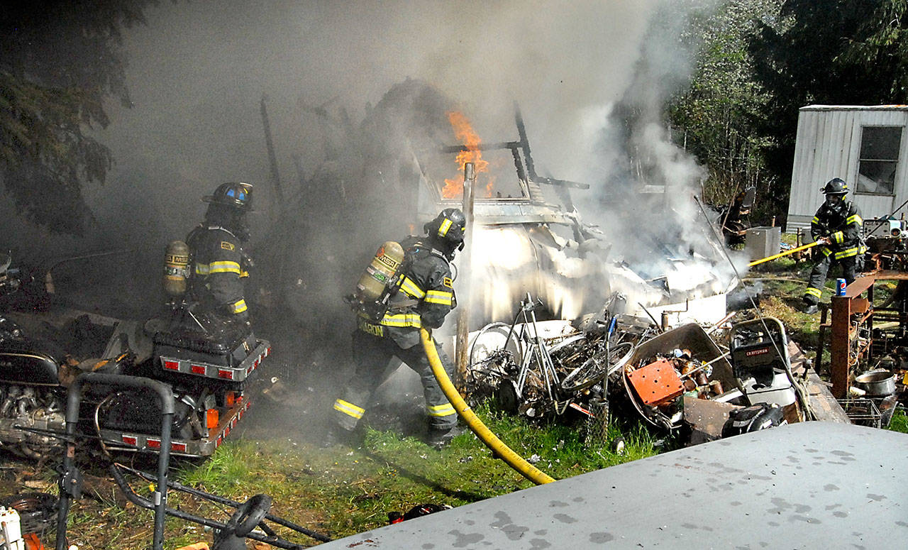 Clallam County Fire District 2 firefighters battle a fire that destroyed a mobile home on Kacee Way west of Port Angeles on Wednesday afternoon. (Keith Thorpe/Peninsula Daily News)