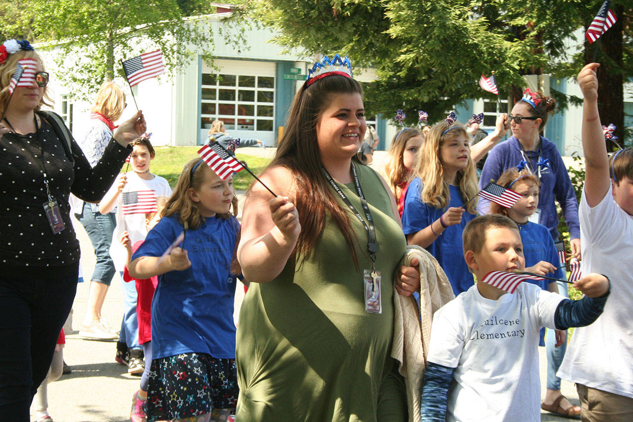 Quilcene Elementary teachers walk with their students and wave flags Friday during the Loyalty Day Parade in Brinnon.