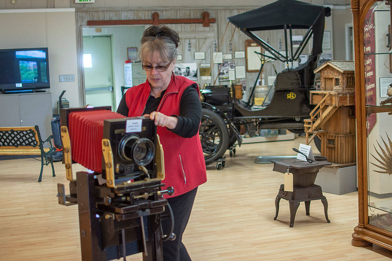 Judy Reandeau Stipe, executive director of the Sequim Museum and Arts Center, moves a camera on display at the museum Sunday. (Jesse Major/Peninsula Daily News)