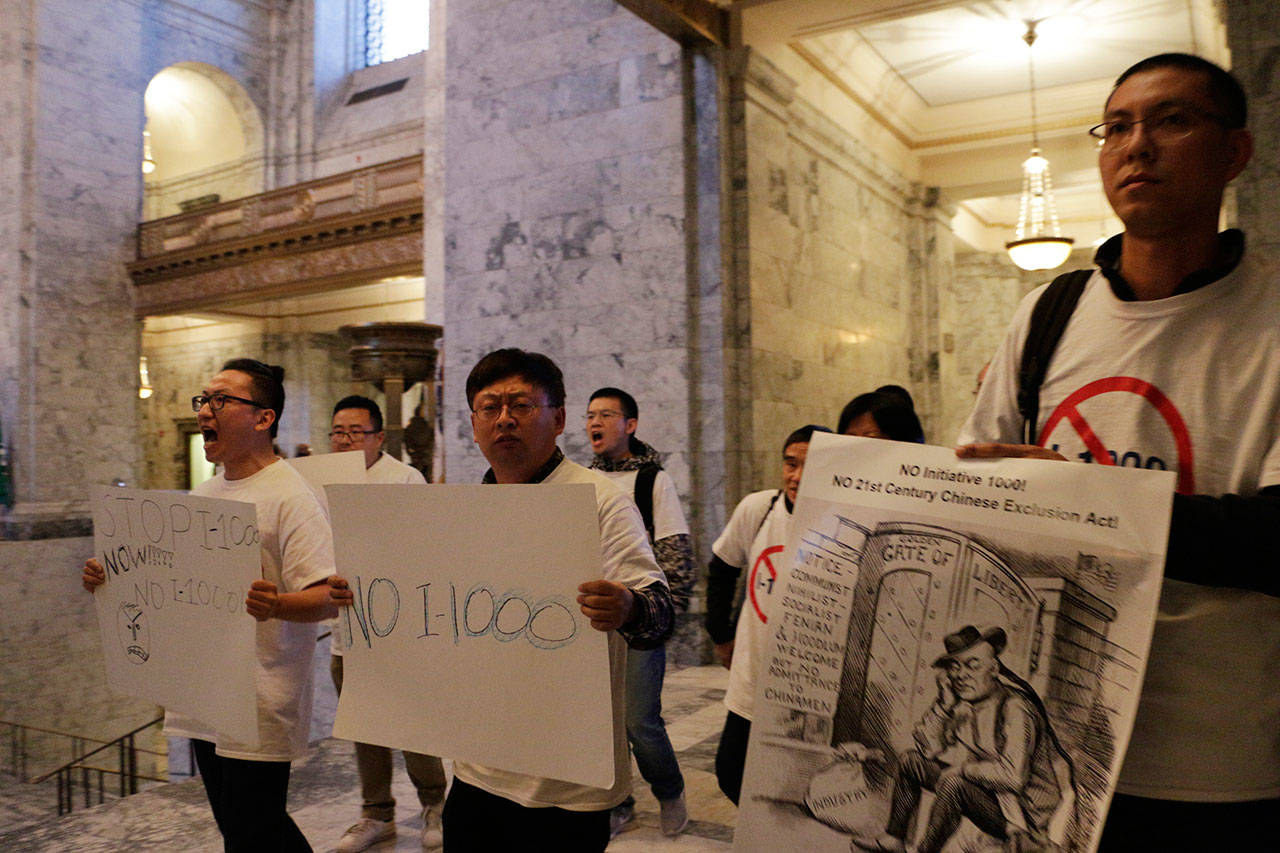 Opponents of an Initiative 1000 march and chant in the Capitol as the Senate debates the measure Sunday in Olympia. (Rachel La Corte/The Associated Press)