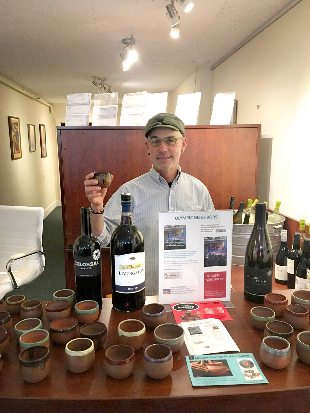 Randy Rosens, Olympic Neighbors board member, serves wine in locally crafted ceramic tasting cups at Coldwell Bankers.