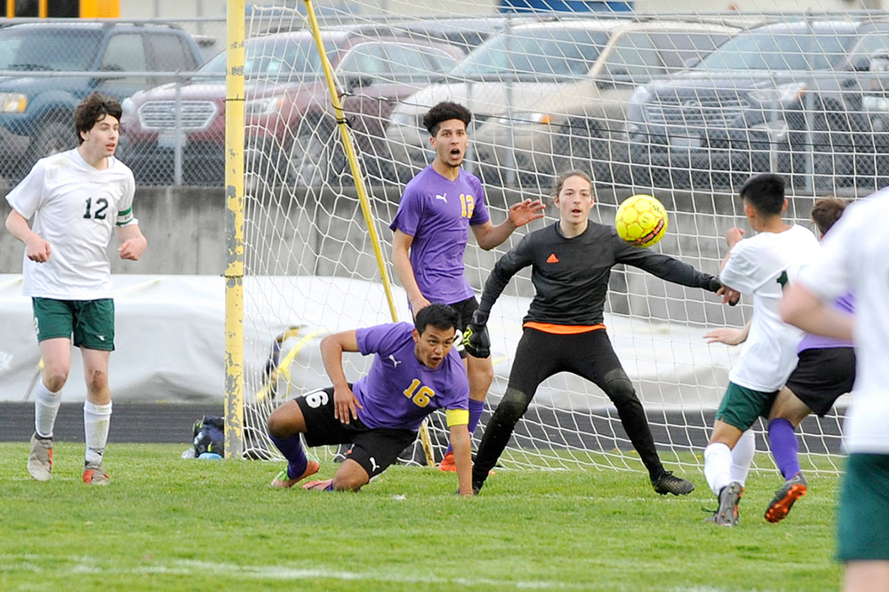 Michael Dashiell/Olympic Peninsula News Group Sequim defenders Rudy Franco, on ground, and Brandon Benson back up Wolves goalkeeper Navy Thomas-Brenske during a game against Port Angeles last month.